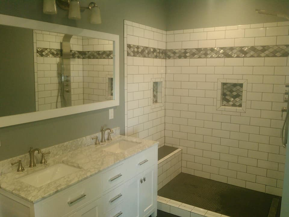 A renovated bathroom featuring a double vanity and a large walk-in shower with subway tiles by Paulus Contracting in Fayetteville, OH