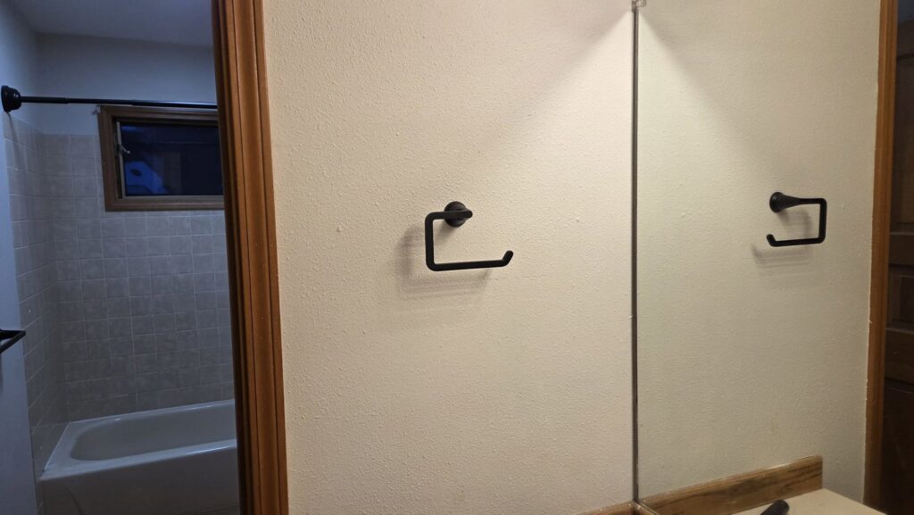 A new black toilet paper holder installed in a bathroom by Infinity Handyman in Anchorage, AK