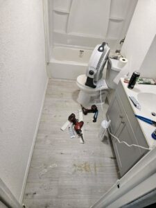 A bathroom undergoing renovation, showing new flooring being installed and fixtures awaiting completion by Mr. Affordable LLC in Denver, CO.