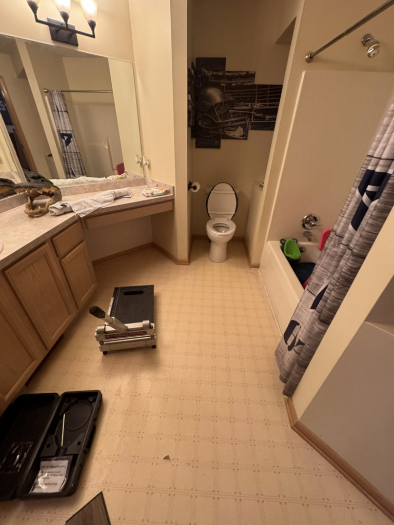 Bathroom floor with old linoleum and tools for new flooring installation by All-In-One Contracting and Home Improvement in Canton, OH