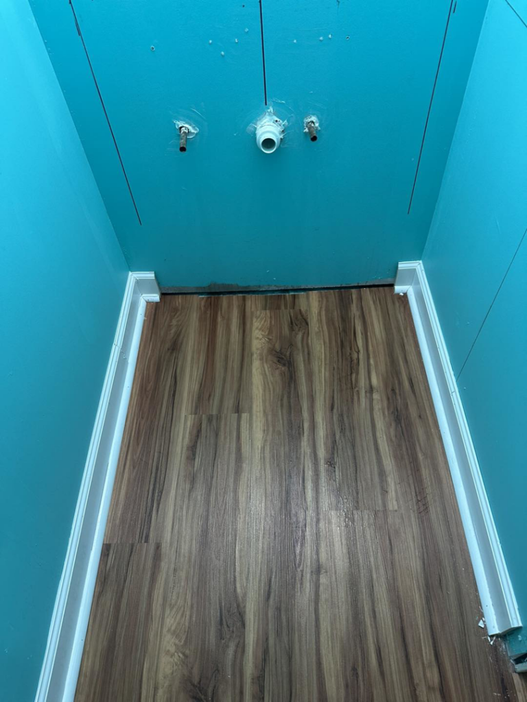 Bathroom floor and baseboards with plumbing connections ready for vanity installation by Quality Home Maintenance Services LLC in Raleigh, NC