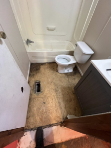 A bathroom with the floor removed down to the subfloor, showing a toilet and bathtub, ready for renovation by Cosa Cleanouts & Junk Removal in Topeka, KS.