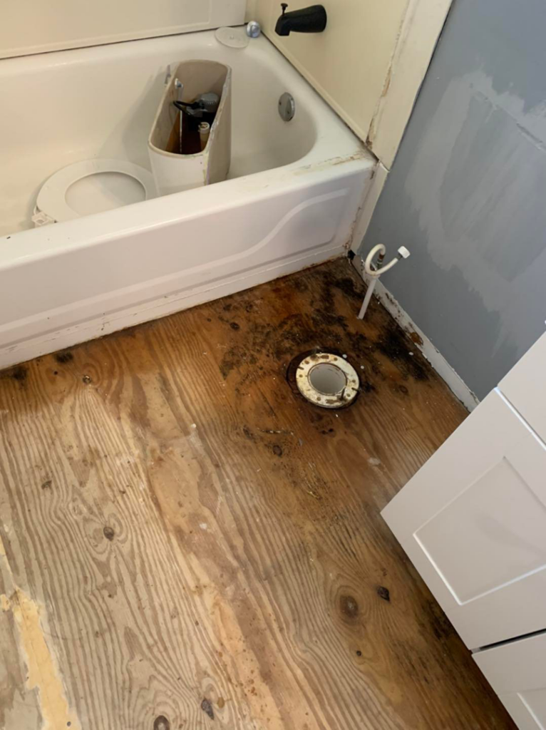 A bathroom floor with exposed subfloor and toilet flange during a renovation project by Humphrey's Helping Hands in Clarksville, TN.
