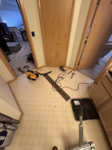 Bathroom floor with tools and new flooring planks during installation by All-In-One Contracting and Home Improvement in Canton, OH