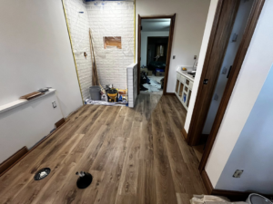 New wood laminate flooring and partially tiled shower walls during a renovation by Fine Line Painting and Design in Georgetown, KY.