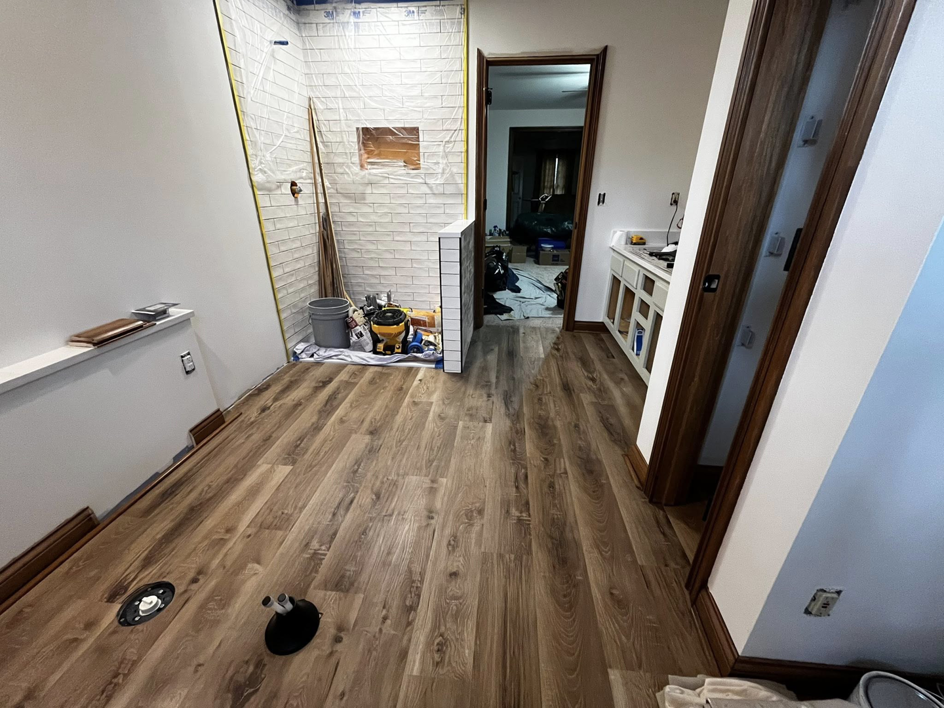 New wood laminate flooring and partially tiled shower walls during a renovation by Fine Line Painting and Design in Georgetown, KY.