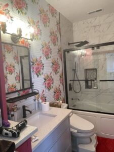 A renovated bathroom featuring floral wallpaper, a modern vanity, and a shower/tub combo by Halpin Hands in Williams, OR.