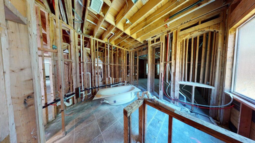 Interior framing of a large bathroom showing plumbing and electrical rough-ins, with a bathtub, under construction by M7 Remodel & Restoration Inc. in Houston, TX