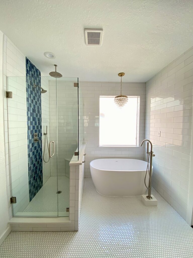 A renovated bathroom with a freestanding tub and a walk-in shower featuring blue accent tiles, completed by Whole House Remodel & Design North Dallas Tx in Frisco, TX.