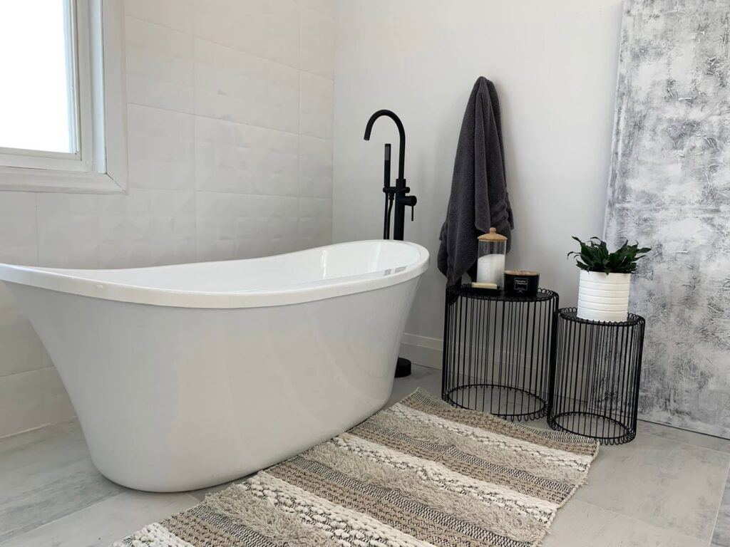 A bathroom featuring a stylish freestanding tub with a black faucet installed by NP General Contracting in Austin, TX.