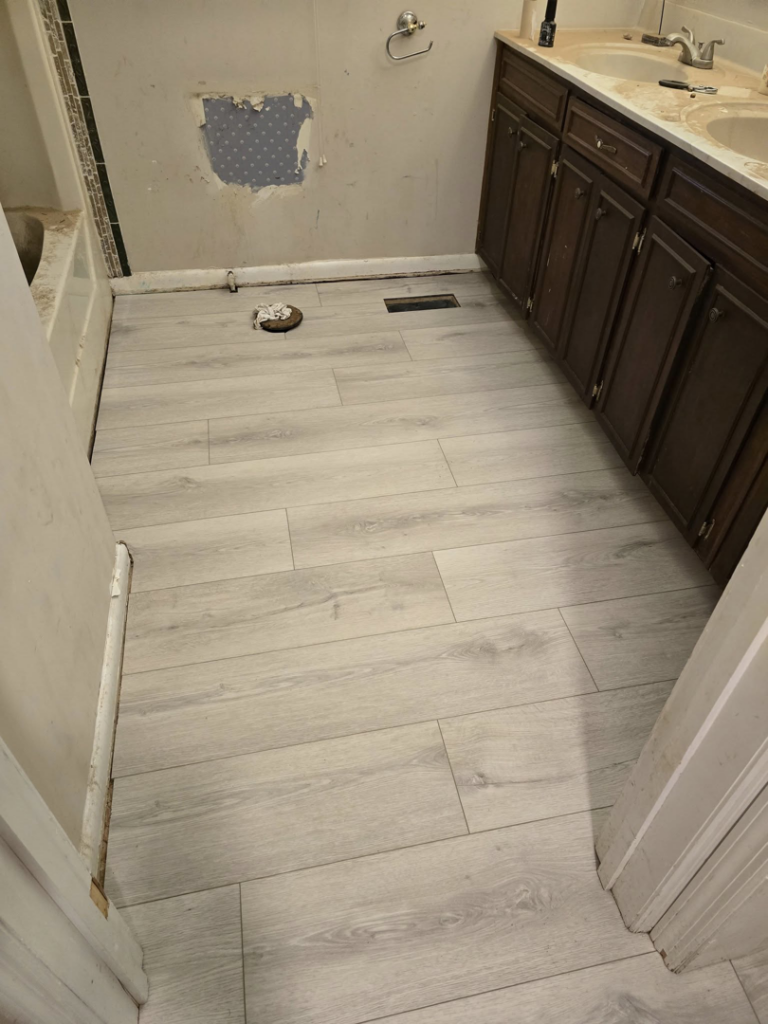 Completed installation of light hardwood flooring in a bathroom by Refined Hardwood Flooring LLC in Wilmington, NC
