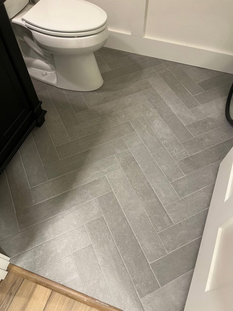 Bathroom featuring stylish herringbone tile flooring installed by D E Custom Floors in Waukesha, WI.