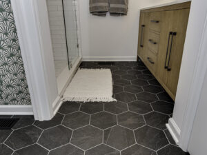 Newly installed black hexagonal floor tiles in a bathroom, a quality flooring service by Boyd's Custom Building in Charlotte, NC.