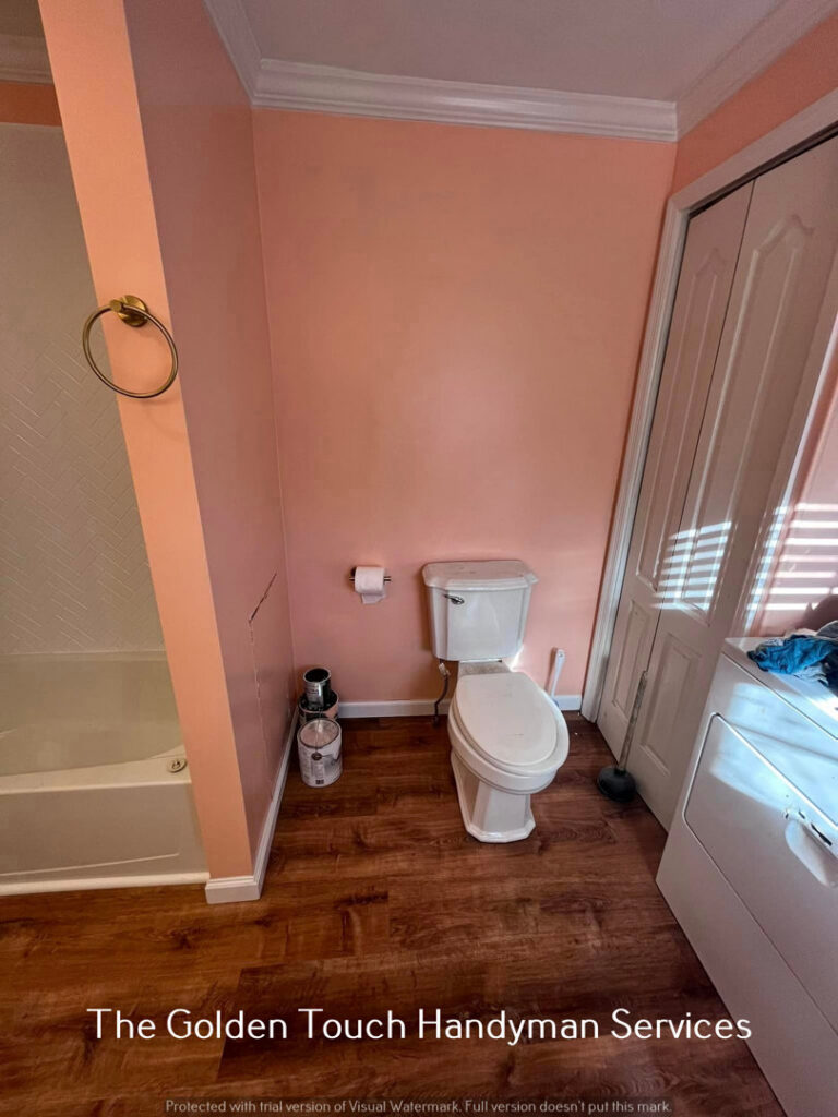 A bathroom and laundry area undergoing renovation, with paint cans visible, by The Golden Touch handyman services in Huntington, WV.