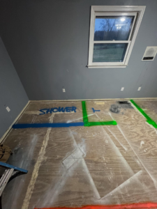 A room under renovation with 'SHOWER' marked on the plywood floor, indicating a bathroom layout by Shackelford Home Designs in Loveland, OH.