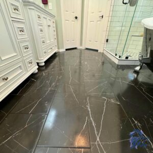 A renovated bathroom showcasing elegant black marble-look tile flooring and white vanities, by Roaring Lion Renovations, LLC in Houston, TX.