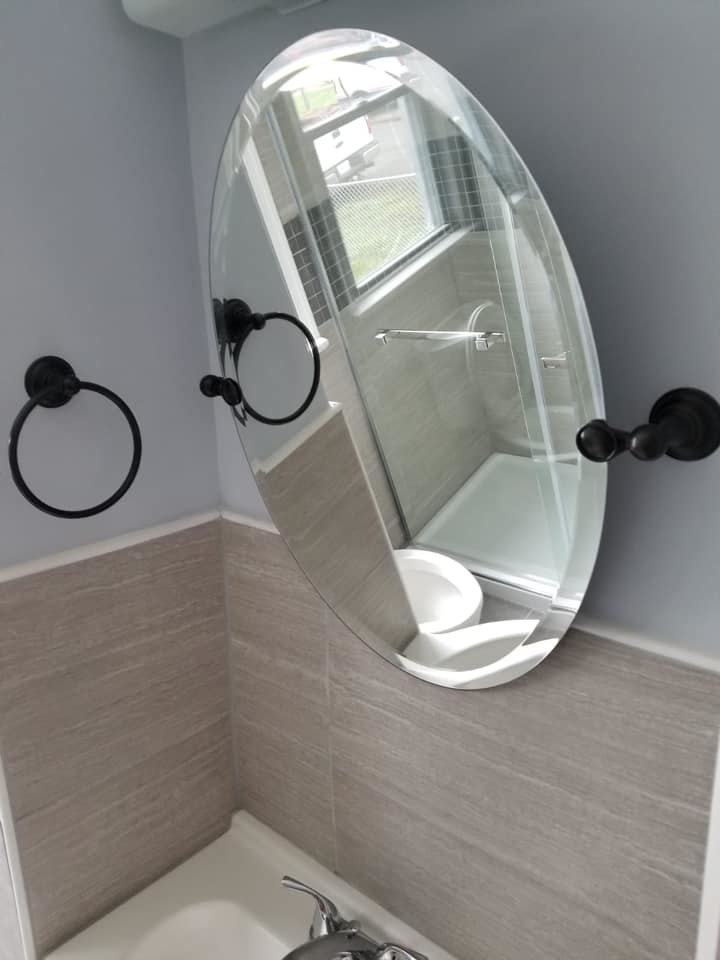 A newly installed oval bathroom mirror and modern faucet, completed by Professional Contractor RVA in Richmond, VA.
