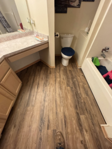 A bathroom featuring newly installed laminate flooring by All-In-One Contracting and Home Improvement in Canton, OH