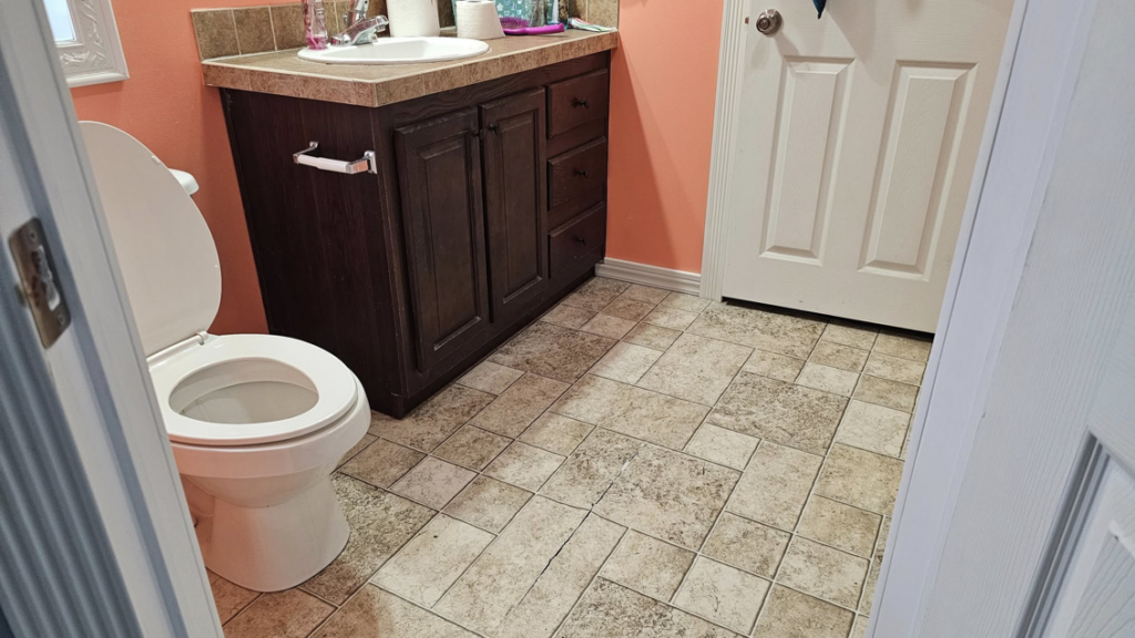 A renovated bathroom featuring new light-colored tile-look flooring installed by Goulds Family Property Management and Handyman Services in Searsport, ME.