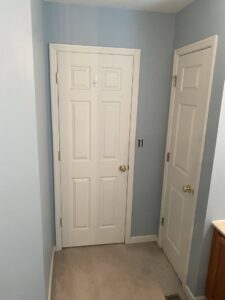 A bathroom with light blue walls and new white doors, showcasing handyman painting and installation services from Newhouse Construction St Louis in St. Louis, MO.