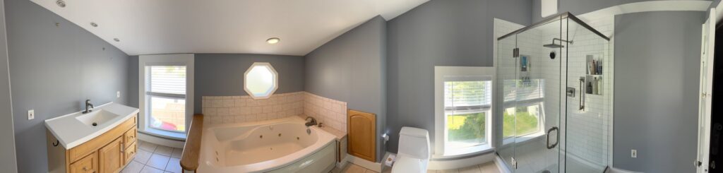 A newly painted grey bathroom with a vanity, jetted tub, and glass shower, completed by SID Painting in West Hartford, CT.
