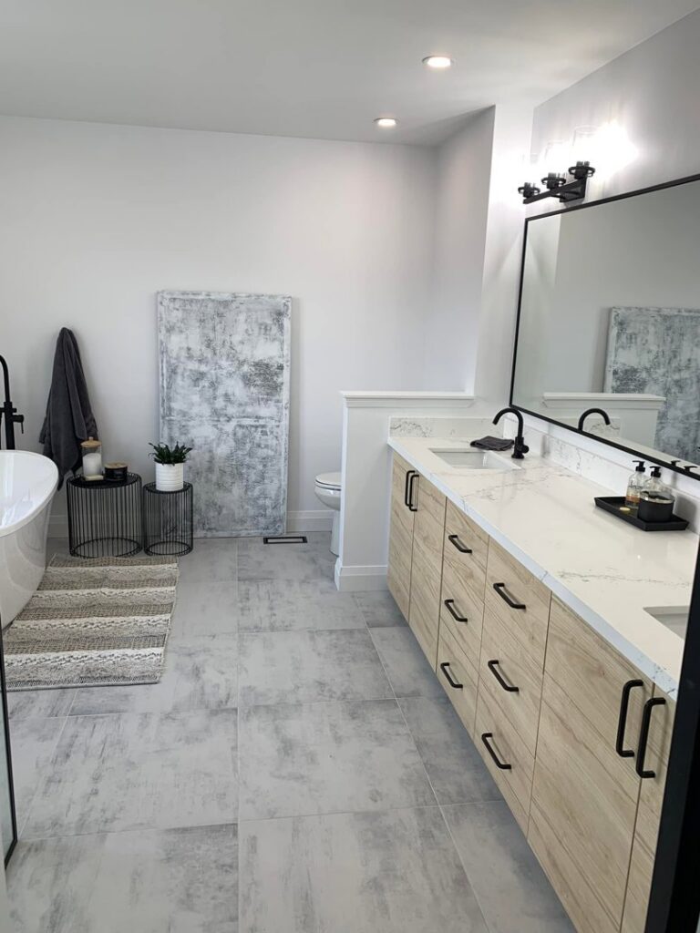 A spacious bathroom remodel with a double vanity, freestanding tub, and tiled floor by NP General Contracting in Austin, TX.