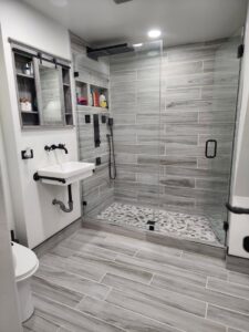 A complete bathroom remodel with a glass shower enclosure and wood-look tile by Luis handyman service in Albuquerque, NM