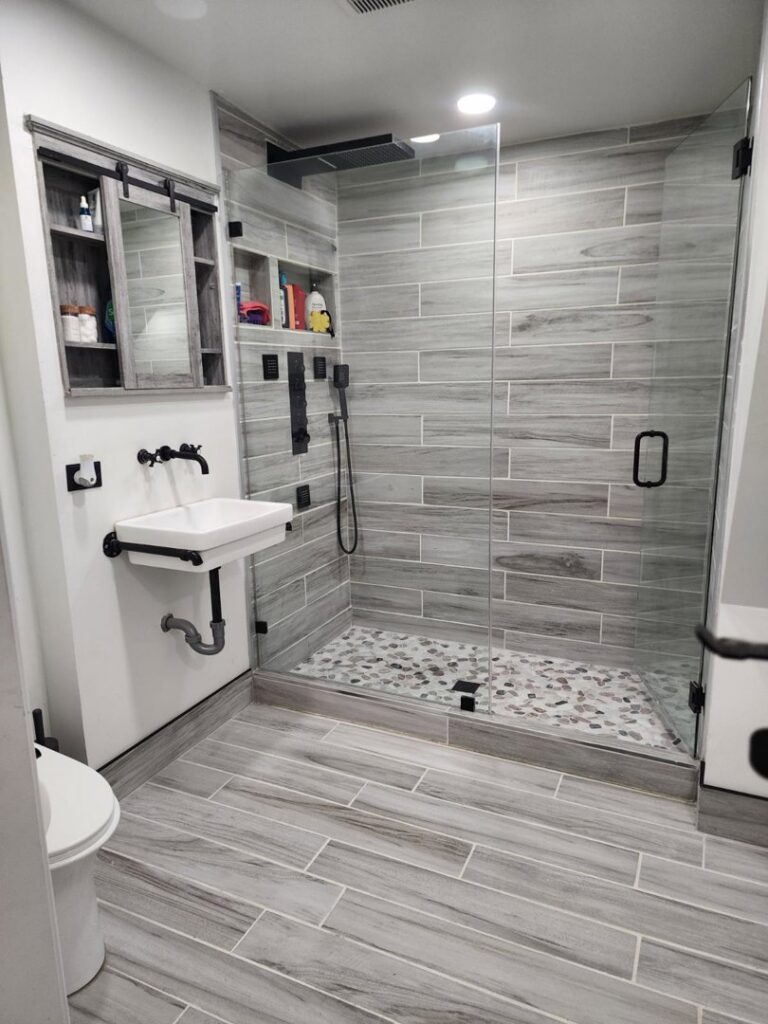 A complete bathroom remodel with a glass shower enclosure and wood-look tile by Luis handyman service in Albuquerque, NM