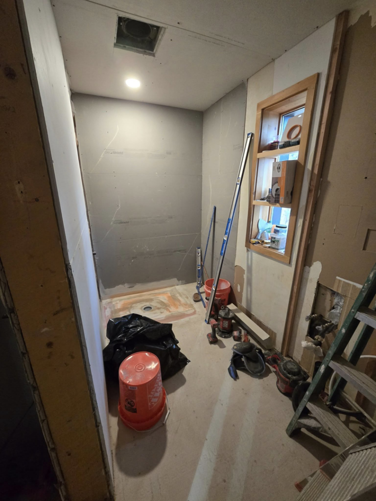 A bathroom remodeling project in progress with new drywall and shower pan by All In Remodeling Services LLC in Arvada, CO.