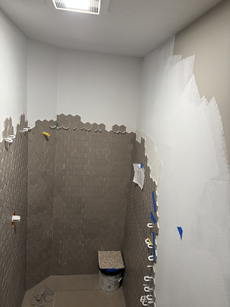 Bathroom remodel in progress showing new hexagonal wall tiles and painted walls by Kaufman Construction in West Des Moines, IA.