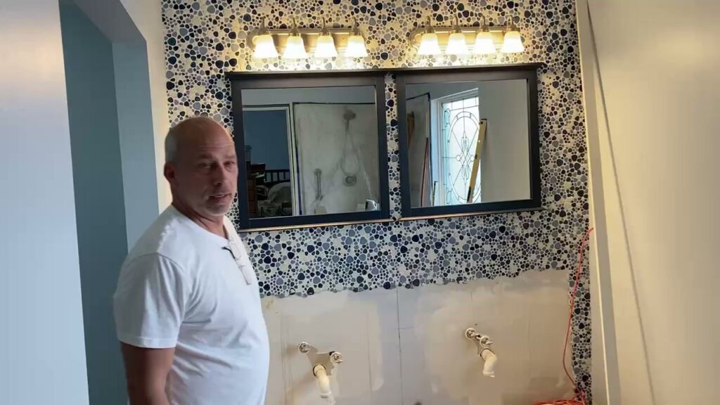 A handyman from Lynden Remodeling working on a bathroom remodel, showing a partially tiled wall and plumbing in Cincinnati, OH