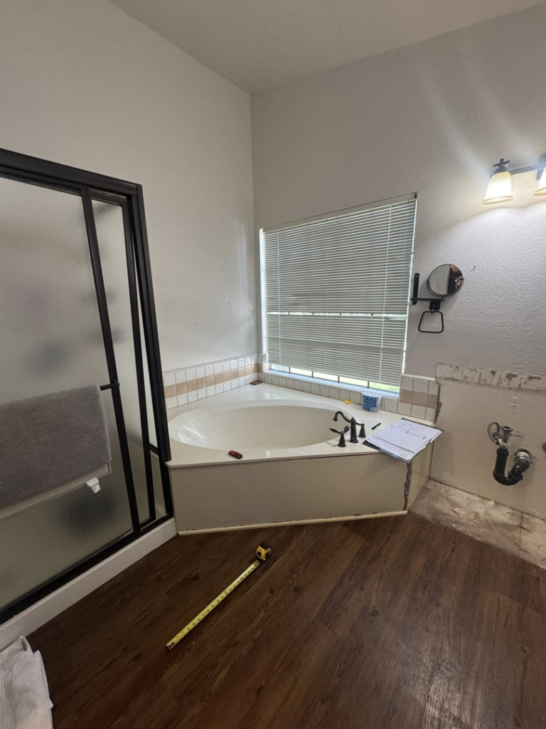A bathroom remodel in progress, featuring a corner tub and shower with partially removed walls by CK Customs LLC in Surprise, AZ.