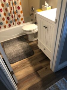 A completed bathroom remodel featuring new flooring and a white vanity by Will.B.More Handyman & Remodel in West Jordan, UT