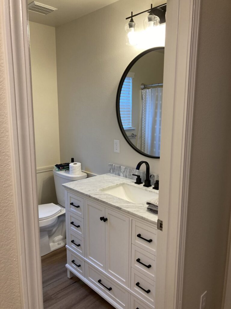 A beautifully remodeled bathroom featuring a new vanity, sink, mirror, and light fixture by Absolute Integrity Handyman Services Inc in Fresno, CA.