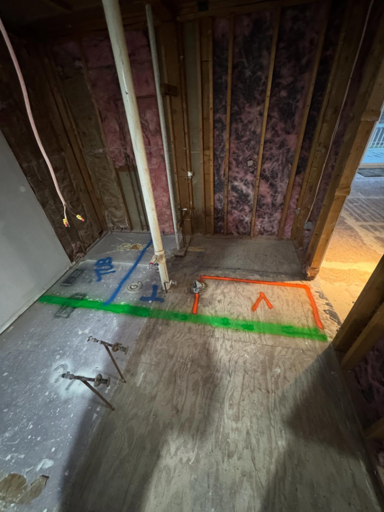 A bathroom remodel in progress, showing exposed plumbing pipes and floor markings for a tub installation by Shackelford Home Designs in Loveland, OH.