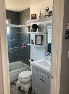 A renovated bathroom featuring a shiplap accent wall, floating shelves, and a new vanity by Absolute Integrity Handyman Services Inc in Fresno, CA.
