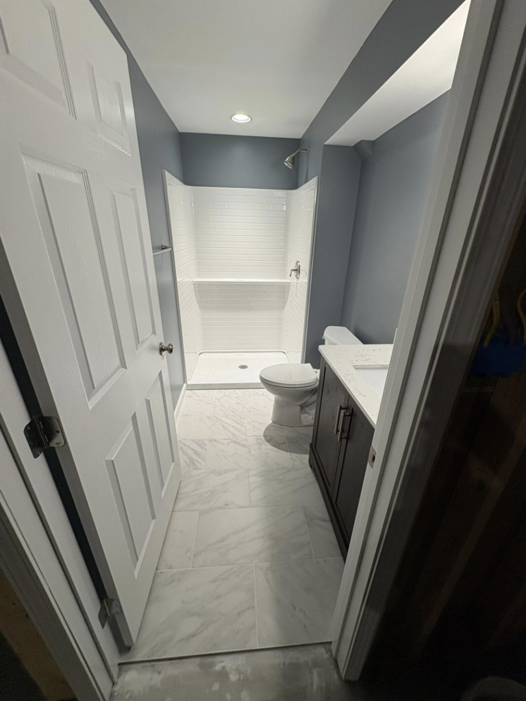 A newly remodeled bathroom featuring a white subway tile shower, new vanity, and modern floor tiles by Fine Line Construction and Remodeling in St. Charles, MO.