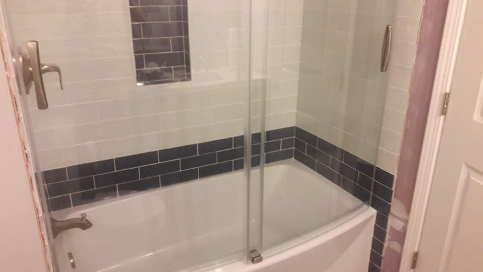 A beautifully tiled bathtub with a new glass enclosure from a bathroom remodel by Capstone Handyman in Sacramento, CA