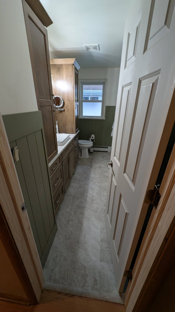A newly remodeled bathroom featuring a modern vanity, toilet, and wainscoting by GCB Home Improvement in Appleton, WI.