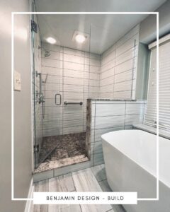A renovated bathroom with a tiled walk-in shower and a modern freestanding tub by Benjamin Design - Build in Fishers, IN.