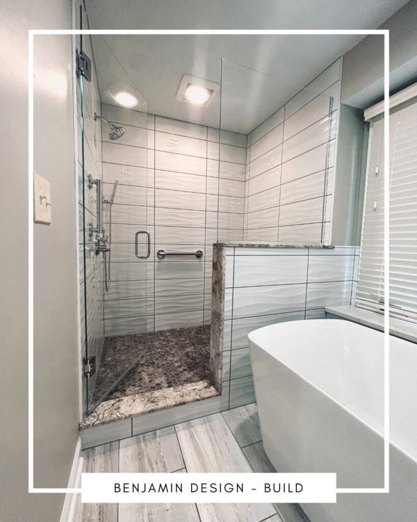 A renovated bathroom with a tiled walk-in shower and a modern freestanding tub by Benjamin Design - Build in Fishers, IN.