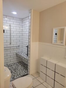 A newly remodeled bathroom featuring a tiled walk-in shower and modern storage by Modern Remodel Build & Design in Worcester, MA.