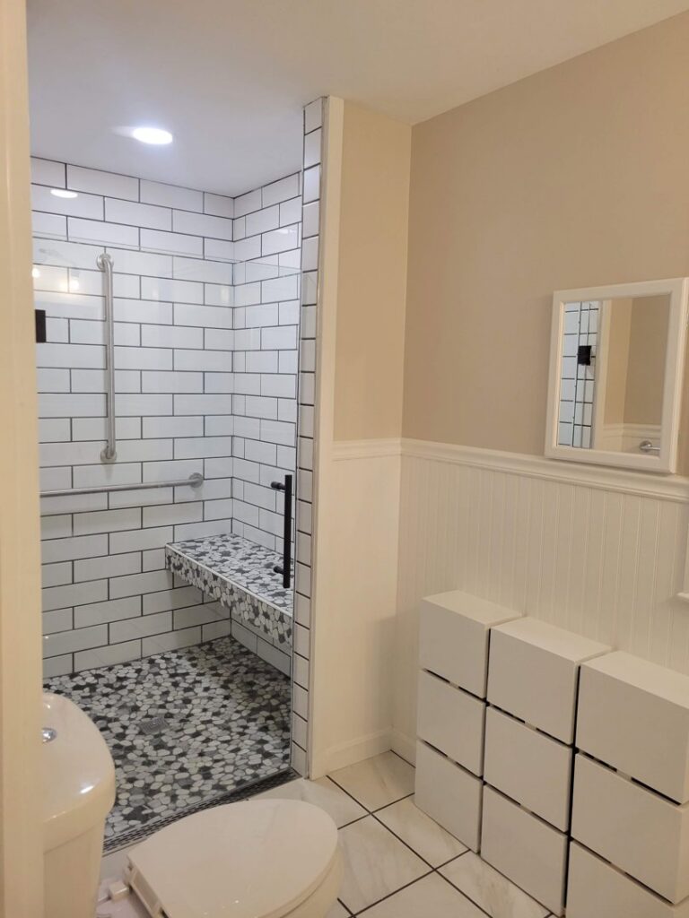 A newly remodeled bathroom featuring a tiled walk-in shower and modern storage by Modern Remodel Build & Design in Worcester, MA.