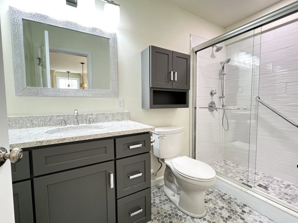 A contemporary bathroom remodel with a walk-in shower and dark grey vanity by Dream Design Build & Remodeling, Inc. in Baltimore, MD