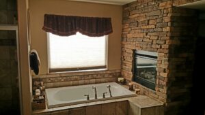 A luxurious bathroom remodel featuring a large tub, stone fireplace, and tiled floor by Advanced Remodeling Services in Elbert, CO.