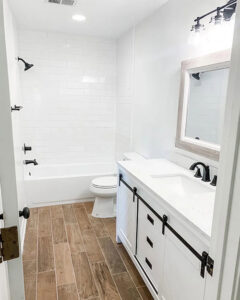 A bathroom remodel featuring a subway tile shower/tub combo and a barn door style vanity by CMT Construction LLC in Columbia, MO.