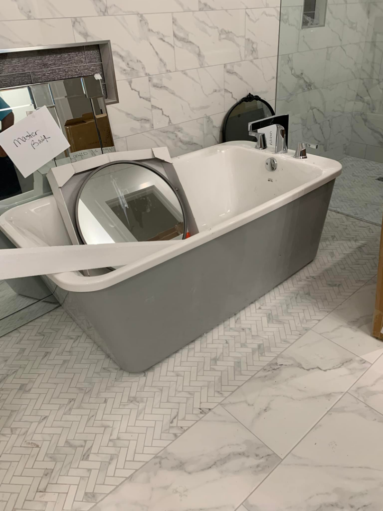 A newly installed freestanding bathtub and marble-look tiles in a bathroom renovation by Baudoin Custom Homes in Lafayette, LA.