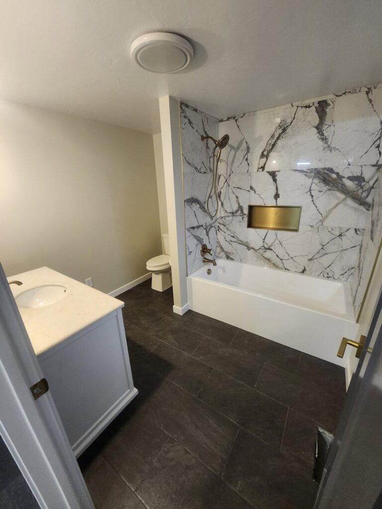 A completed bathroom renovation featuring a new bathtub, marble-look tile, and vanity by Joe's Handyman Solutions in Ogden, UT.