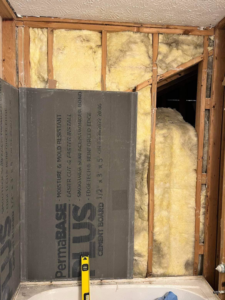 Bathroom walls stripped to studs with insulation and cement board being installed for a shower, a renovation project by JB Recovery in Columbus, OH.