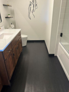 A renovated bathroom featuring a dark floor and wooden vanity by VanVleet Construction in Brooklyn Park, MN.